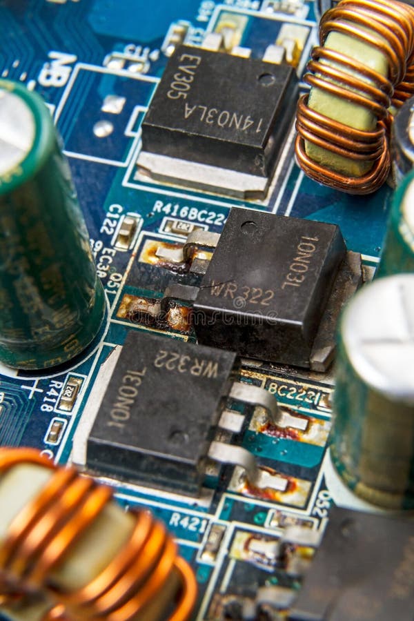 Blown MOSFET transistor 10N03L. On a computer motherboard. Manufacturer labeling is absent stock photos