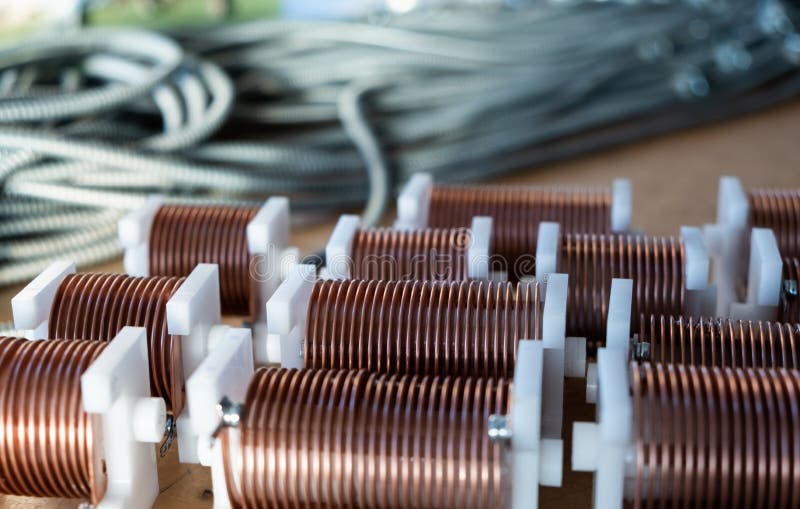 Close-up of twisted copper wire coils. Close-up of high-frequency powerful copper wire on background of numerous blurry cables. Concept production of super stock photography