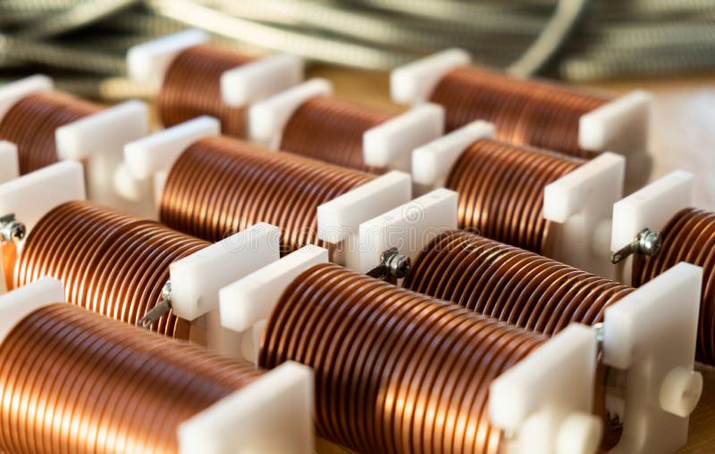 Close-up of twisted copper wire coils. Close-up of high-frequency powerful copper wire on background of numerous blurry cables. Concept production of super stock photos