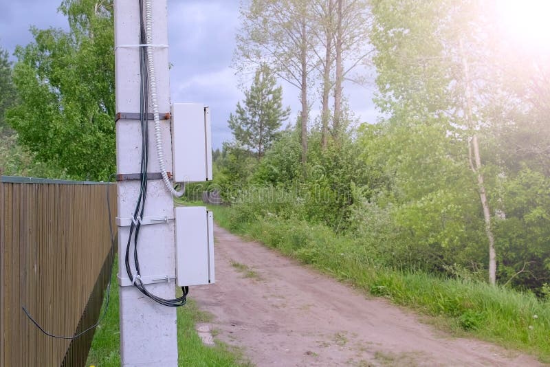 Electric shield on a street pole in the private sector, closeup view. Electric pole on a country road in the village near the fence. Modern equipment for stock photos