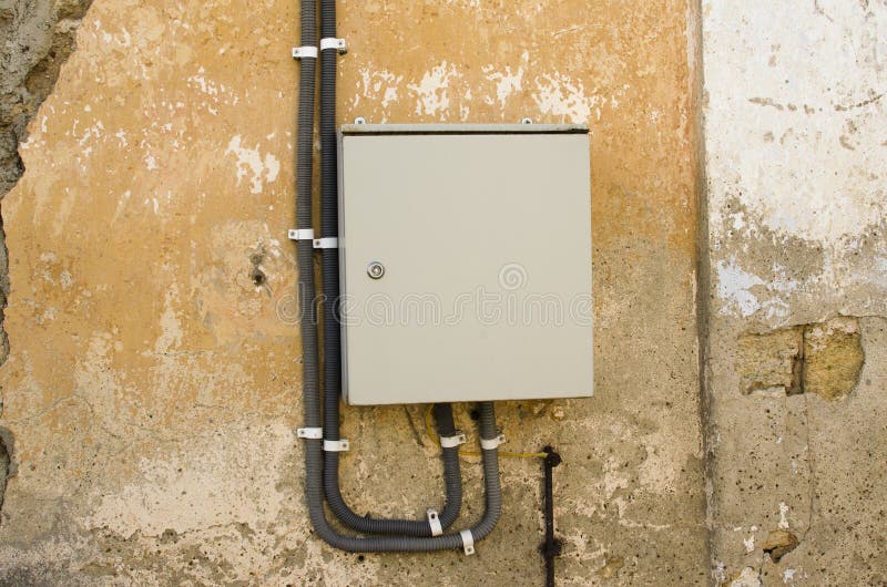 Electric shield on the wall of an old house. Gray electric shield on the wall of an old house royalty free stock photo