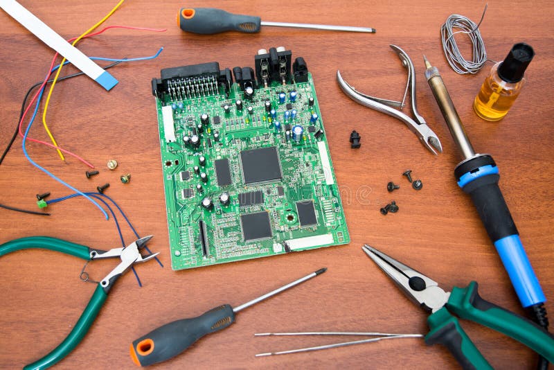 Electronic system board with microcircuits and electronic components. Necessary tools for repair. stock photos