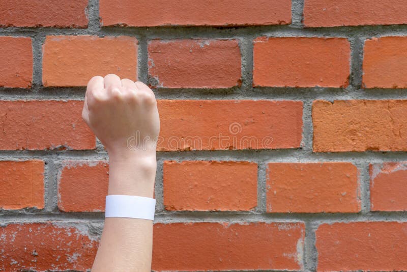 Hand clenched into a fist on a background of a brick wall. A sign of perseverance and resistance.  royalty free stock image