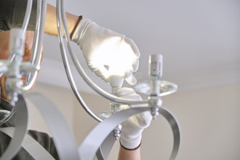 Installation ceiling lamp, hands of electrician fixing chandelier. Installation ceiling lamp, hands of male electrician fixing chandelier with use of royalty free stock photos