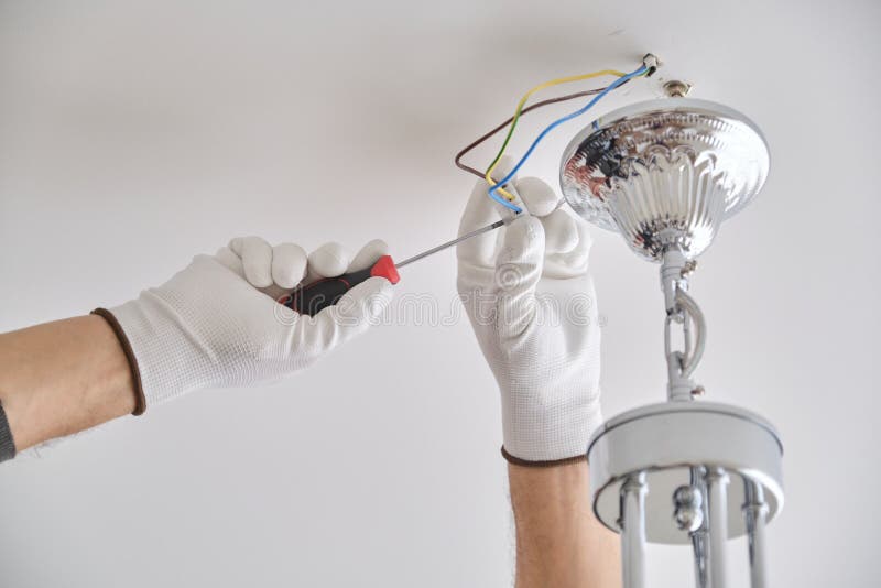 Installation ceiling lamp, hands of electrician fixing chandelier. Installation ceiling lamp, hands of male electrician fixing chandelier with use of royalty free stock image