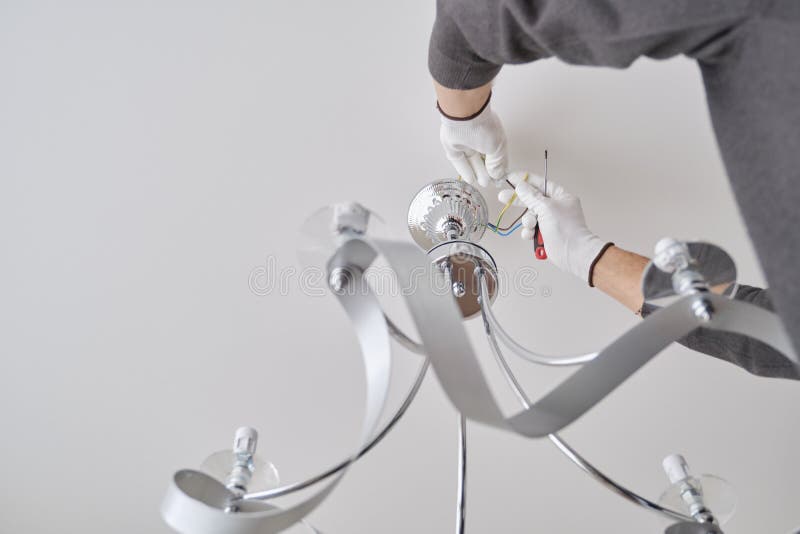 Installation ceiling lamp, hands of electrician fixing chandelier. Installation ceiling lamp, hands of male electrician fixing chandelier with use of royalty free stock images