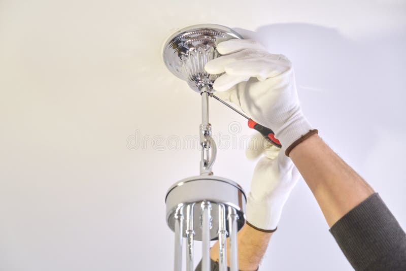 Installation ceiling lamp, hands of electrician fixing chandelier. Installation ceiling lamp, hands of male electrician fixing chandelier with use of royalty free stock photos