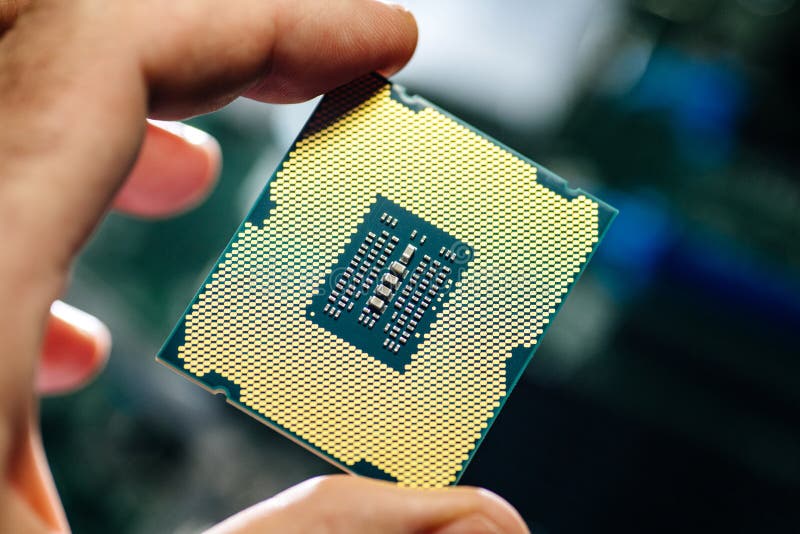 Man holding powerful CPU processor for computer. Man hand IT engineer holding against technological motherboard background new professional golden CPU processor stock images