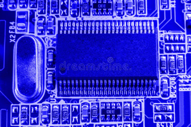 Microchip and quartz on the motherboard of a modern computer blue background close macro.  stock images