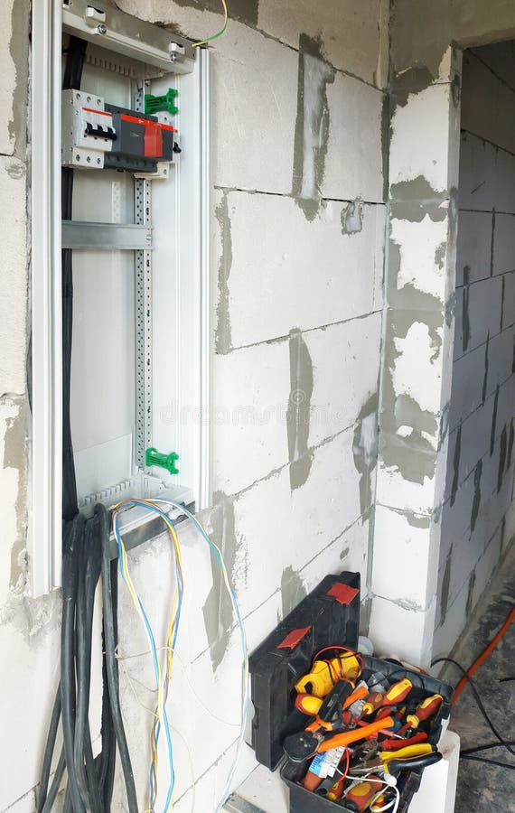 A new electric shield is installed on the wall of the newly built house, cables and tools are visible. 2019 royalty free stock photo