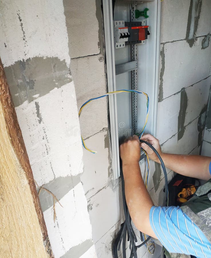 A professional electrician joins an electric wire to a power shield. 2019 stock photo