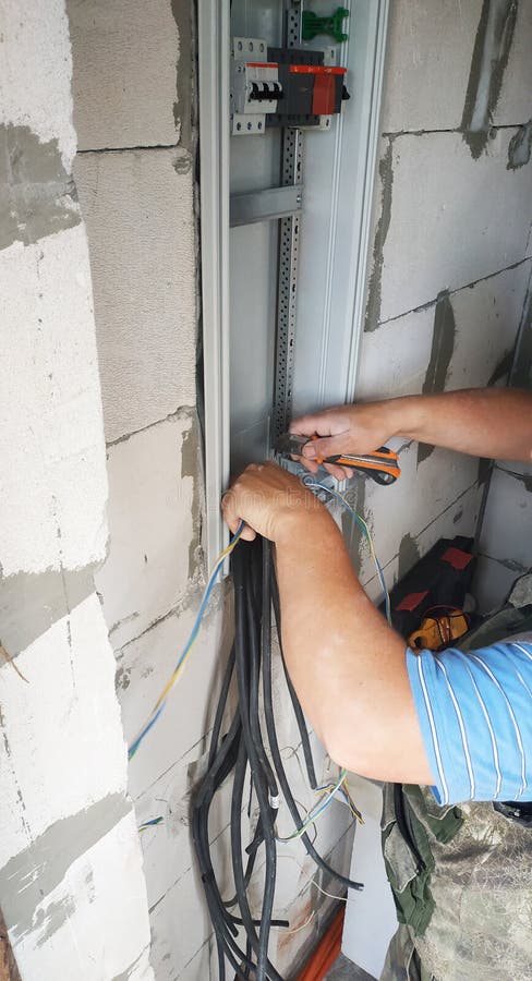 A professional electrician joins an electric wire to a power shield. 2019 stock image
