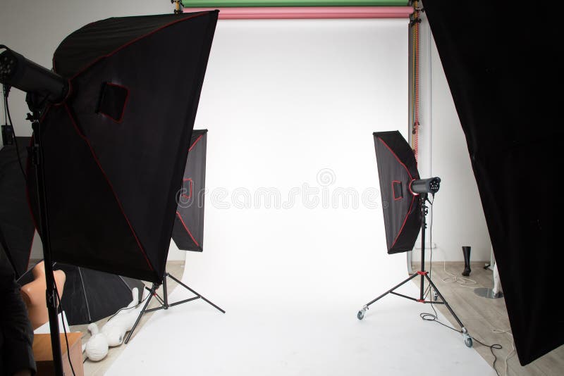 Studio lighting devices are installed in the photo Studio for photography. White paper background is hung on the wall and rolled out on the floor royalty free stock photography